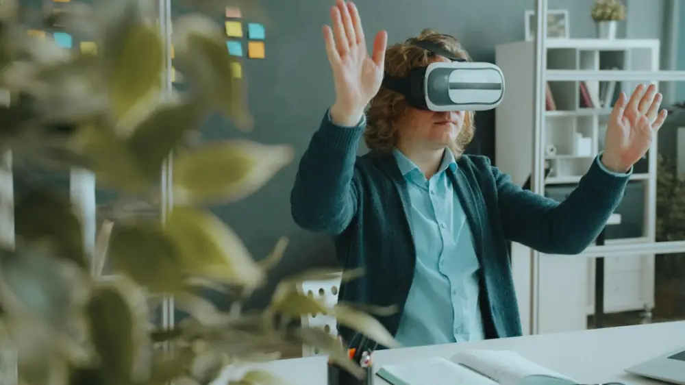 A person with curly hair wearing a virtual reality headset in a workspace, illustrating virtual CIO (vCIO) services
